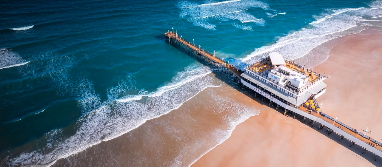 Aerial view of Daytona Beach pier and waves along the shoreline