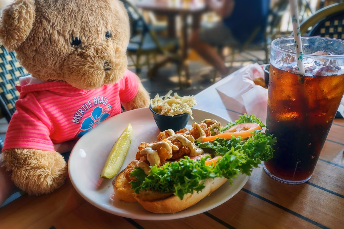 Myrtle Beach dining scene with a teddy bear, seafood meal and drink